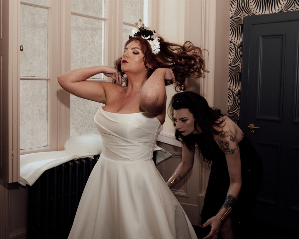 A bride flicks her hair as her bridesmaids adjusts her dress. Top tips for great wedding photographs.