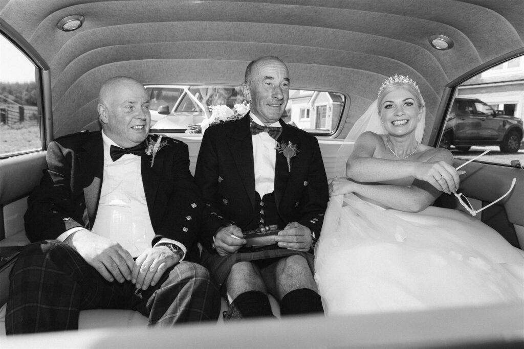 A bride with her dad and step dad in a cadilllac. 