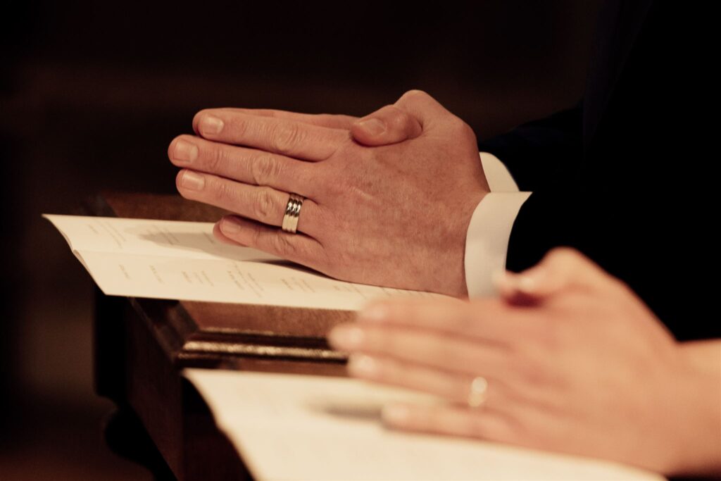 A couples hands as they pray on their wedding day. The photo shows just their hands.