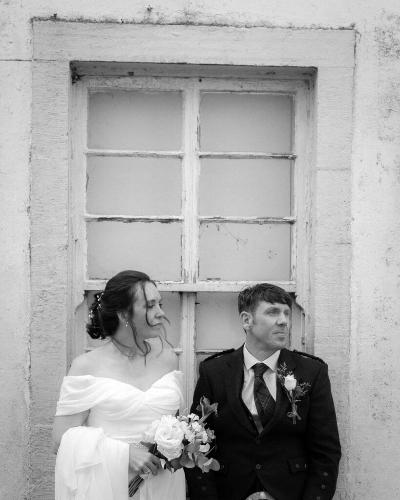 A couple stand by a window artistically